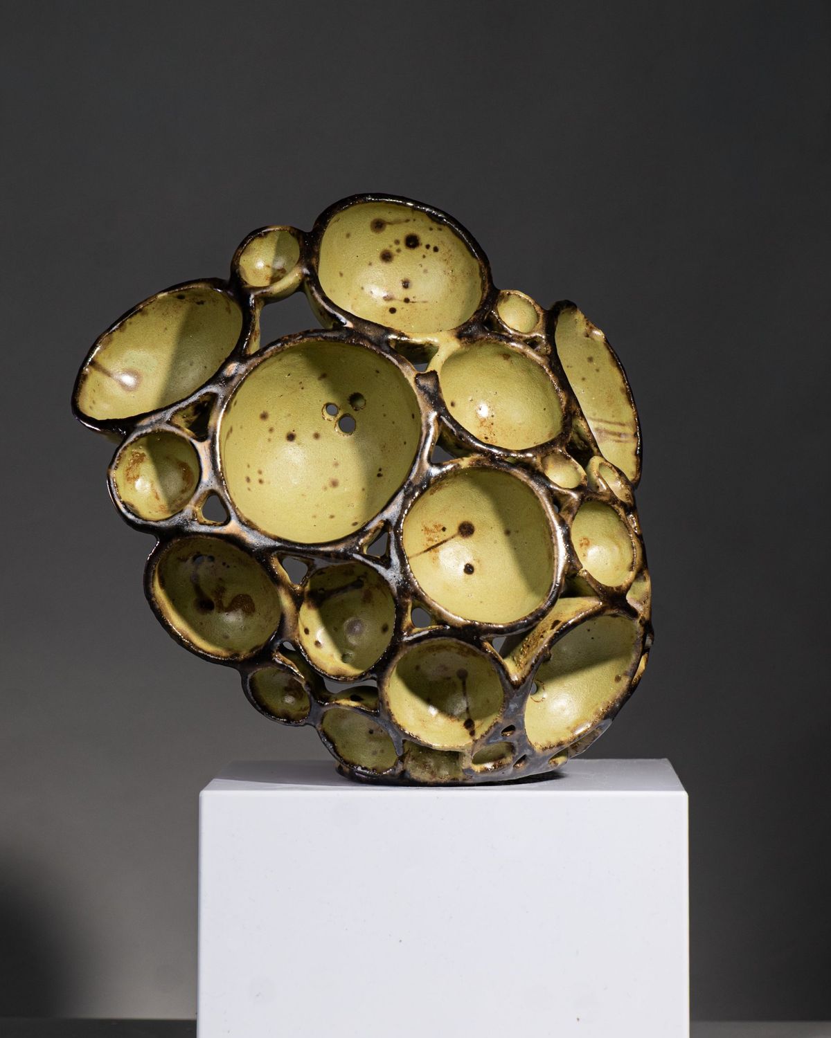 Olive green glazed sculpture made of clustered bowl forms