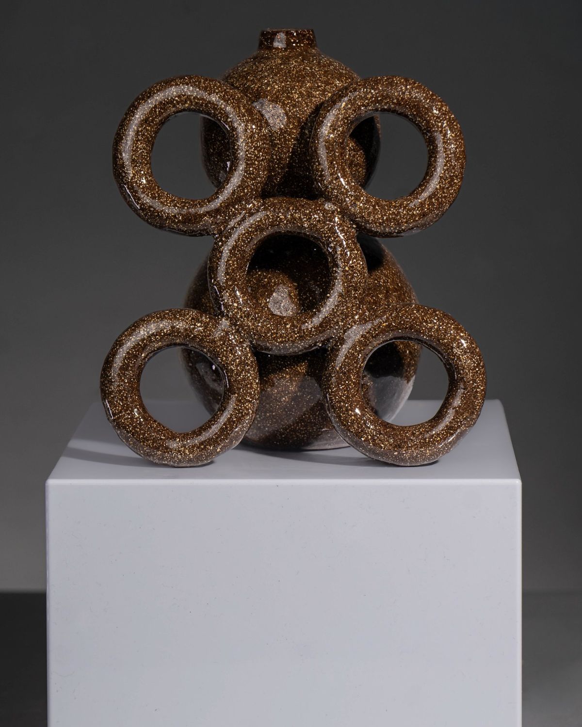Dark speckled glazed vessel with five ring forms